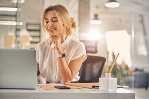 Blonde woman wearing a smartwatch working on a laptop